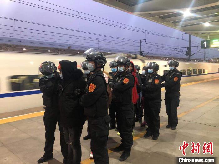 9名身着便衣的民警押解着4名犯罪嫌疑人走下动车，在站台上将4名犯罪嫌疑人交由其他民警进行押解。　李庭耀 摄