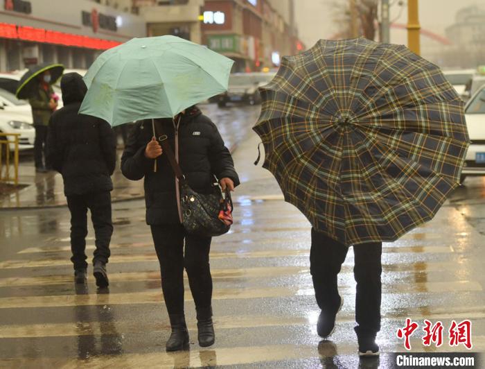 泥雨俱下，市民撑伞出行。　张瑶 摄