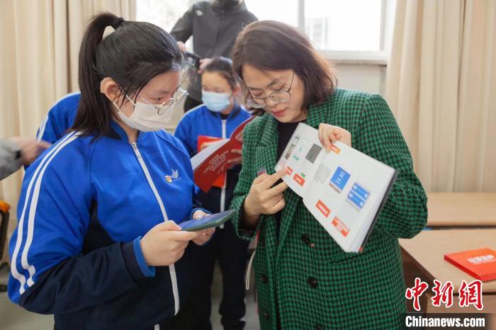 在北京市东城区特殊教育学校，项目工作人员为受助学生讲解“爱畅聊”智能通话助理使用方法。　杨燕红 摄