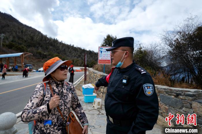 图为警务室民警为游客讲解景区内的相关注意事项。　江才云旦 摄