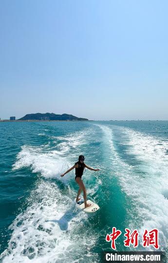 造浪船激起的浪花里，冲浪者不需牵绳即可滑行。　尹好 摄