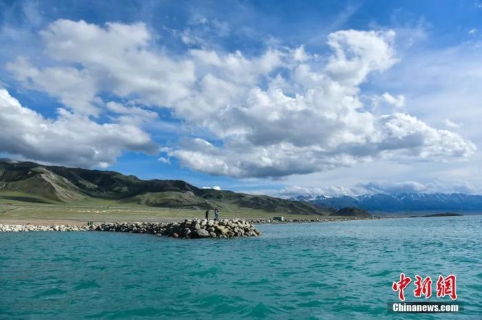 游客在赛里木湖景区欣赏夏日美景。中新社记者 张兴龙 摄