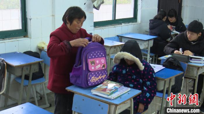 3月5日，汪桂月(左一)把孙女婷婷送到教室后，帮着孙女整理书本。　刘鸿鹤 摄