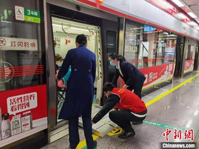 地铁工作人员正在帮助老年人乘客铺设轮椅踏板。　郑江洛 摄