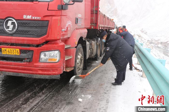 民警利用煤粒等物资对结冰路面化冰，随后对滞留车辆进行分流疏导。　王振 摄