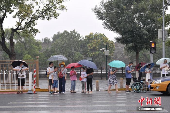 图为北京景山前街，民众冒雨出行。中新网记者 李骏 摄