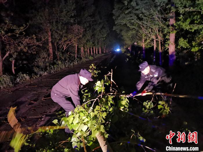 30日晚，如东县经济开发区派出所民警王玉军、辅警张海峰第一时间在辖区公路清理沿途被大风吹断的树木。　警方供图 摄