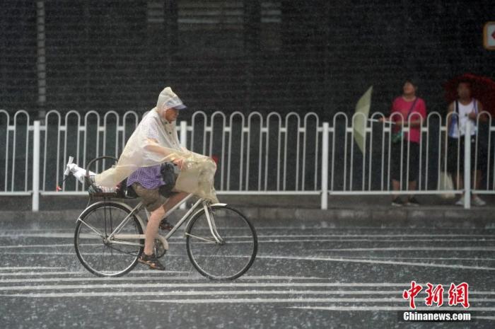 资料图：北京市门头沟区，市民雨中骑行。中新社记者 张兴龙 摄