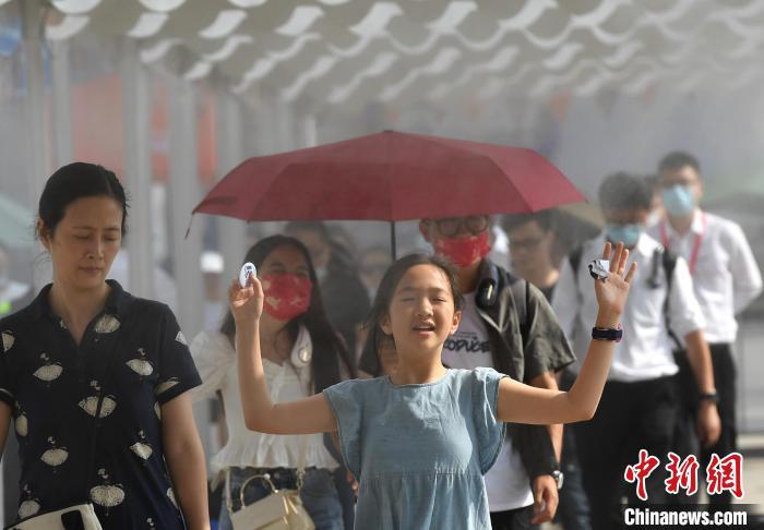 资料图：6月12日，重庆气温创新高 室外最高温超35℃，图为一小朋友经过广场上的水雾降温区域。　陈超 摄