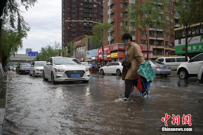 6月2日，吉林省长春市遭遇暴雨，城区多个路段积水成河，多台车辆被困水中抛锚。当天，吉林省气象台发布暴雨、冰雹、雷暴大风、城市内涝风险等天气预警。图为市民在积水路段通行。 张瑶 摄