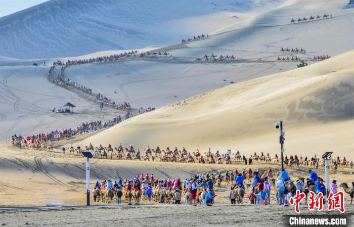 游客在敦煌鸣沙山月牙泉景区骑骆驼观光游览，形成近2公里长的观光驼队。(资料图) 王斌银 摄