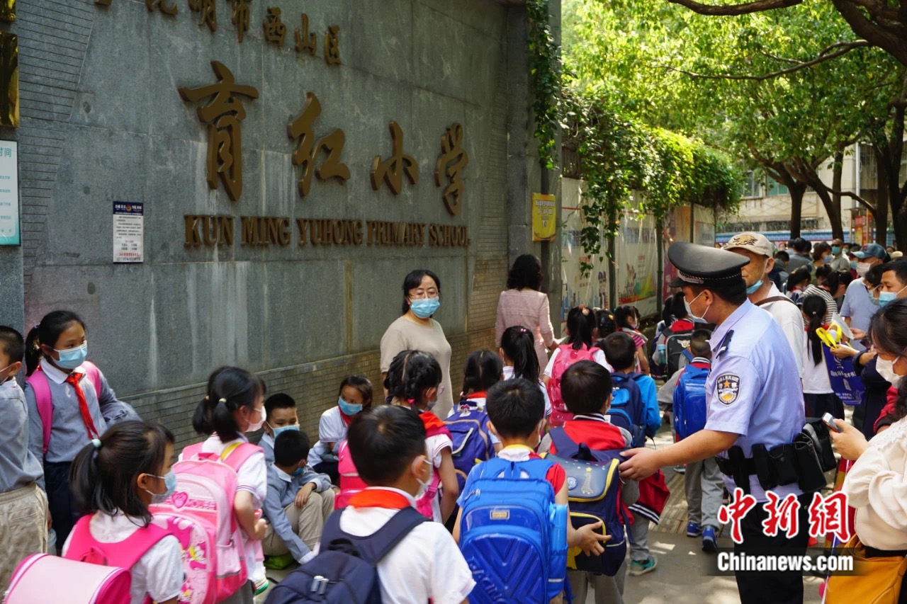 　图为民警协助老师，为学生出行护航。杨芳摄。