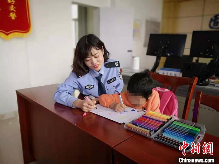 图为民警陪着小女孩画画。　包头市公安局交警支队固阳大队供图