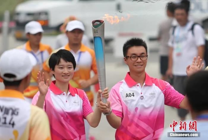 2014年8月12日，跆拳道奥运会冠军吴静钰(左)与丈夫侯琨在进行青奥会火炬传递。中新社记者 泱波 摄