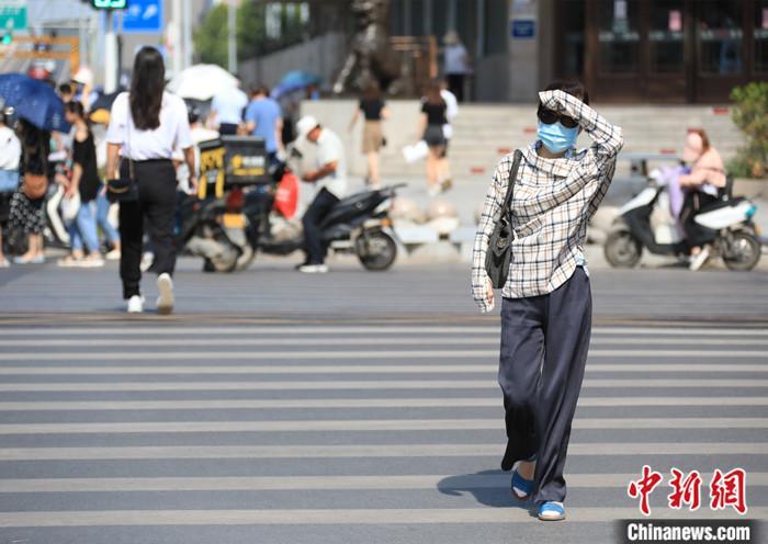 资料图：出行的市民遮挡烈日。 中新社记者 刘鹏 摄