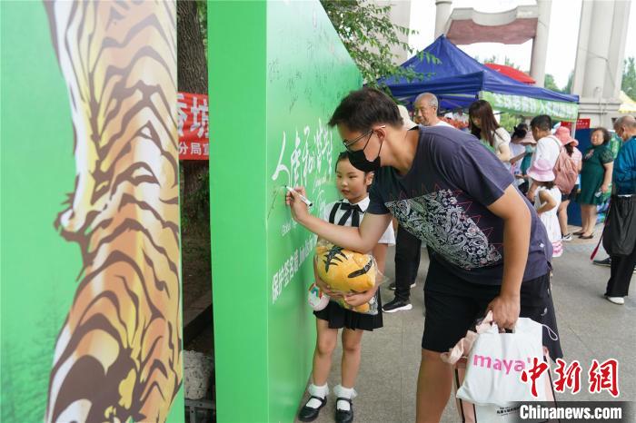 图为民众在“人虎和谐共生”展板上签名 吕品 摄