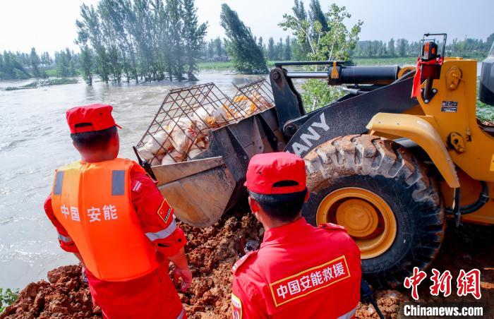 大型推土机在决口处倾倒装满石料的钢筋笼 张畅 摄