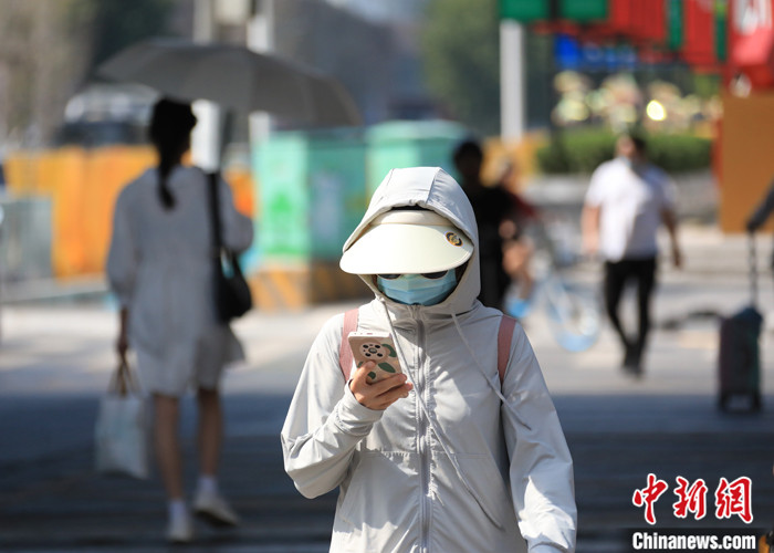 7月9日，郑州，市民遮挡严实防晒出行。 中新社记者　刘鹏 摄