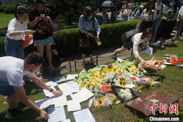 青年们来到烈士墓区祭扫，为赵世炎烈士敬献鲜花、擦拭墓碑。　上海龙华烈士陵园供图