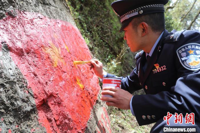 图为玉麦边境派出所移民管理警察在边境一线对国旗、中国字样等主权标志物描红。　山南边境管理支队供图