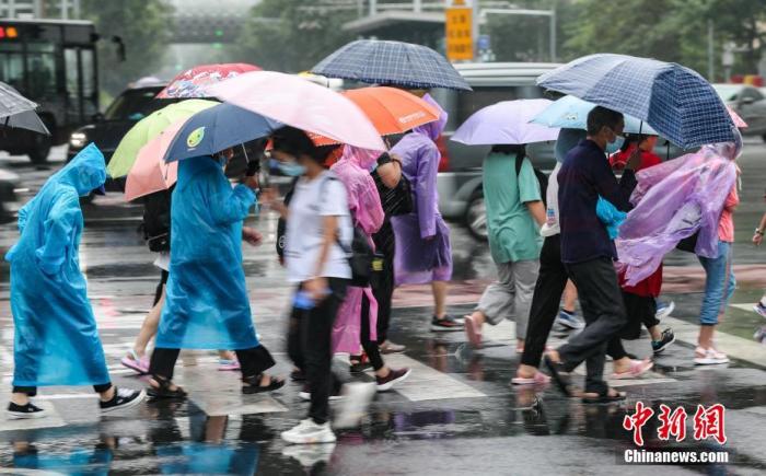 7月12日，北京朝阳区团结湖附近，民众通过路口。从11日夜间开始，北京迎来入汛以来最强降雨天气。 中新社记者 贾天勇 摄