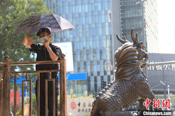 7月9日，郑州，一名保安撑伞遮阳工作。 中新社记者　刘鹏 摄