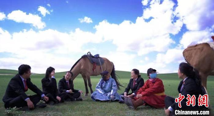 图为法官在草原上席地而坐。　太仆寺旗法院供图