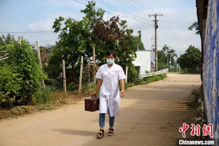 潘秋梅提着医药箱去村民家里随诊。　朱柳融 摄