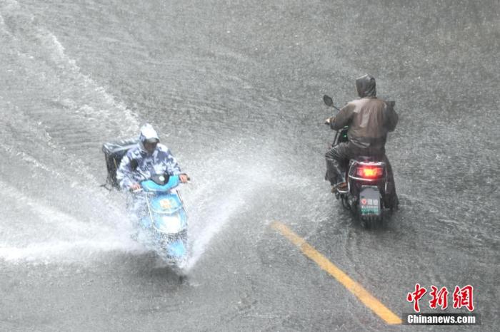 资料图：市民在积水路段骑车出行。王东明 摄