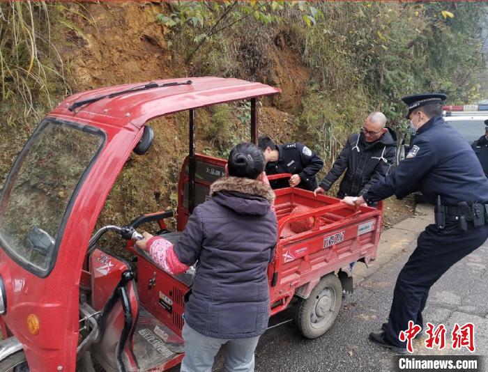 民警帮助三轮车驾驶员将车从边沟抬出来。　落别乡派出所供图