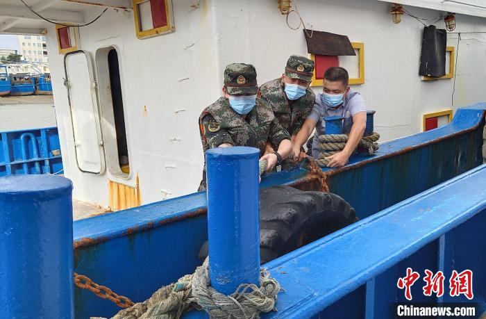 图为海警执法人员在漳州龙海石码港帮助渔民加固船上船缆。　漳州海警局 供图