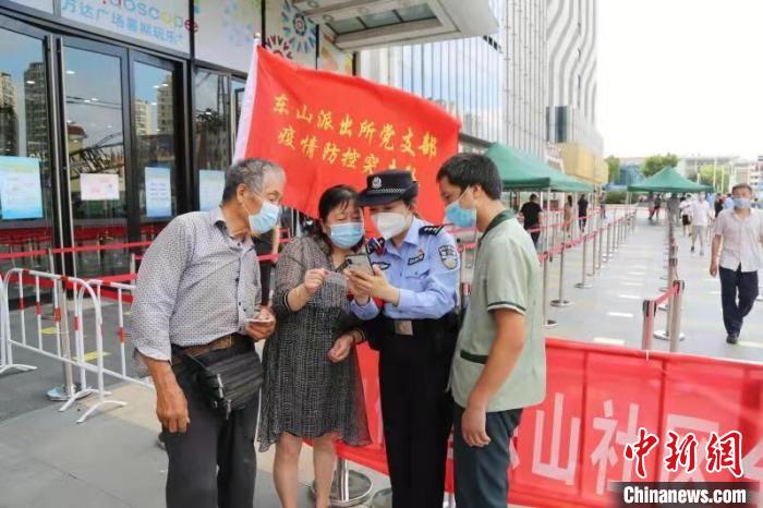 图为警方指导市民查询行程码。　潘冉东 摄