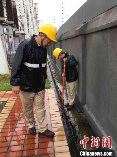 图为运维人员冒着大雨在220千伏建新变电站内疏通排水系统。　陈蒸 摄