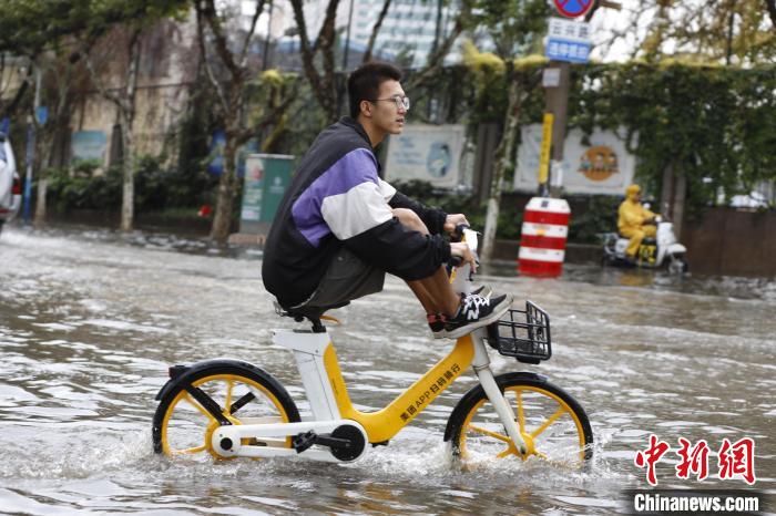 图为8月9日，昆明市民经过淹积水路段。　李嘉娴 摄