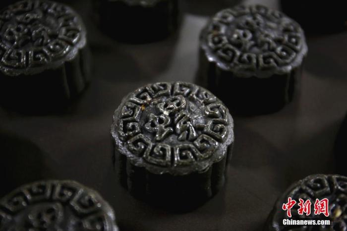 图为9月16日，广西柳州市一家烘焙生产企业生产的螺蛳粉月饼，饼皮用墨鱼汁着色。 中新社记者 朱柳融 摄