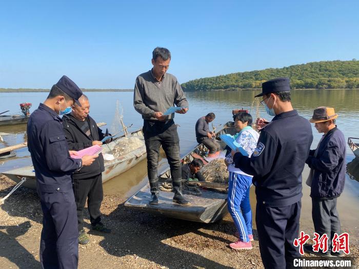 民警向渔民发放禁渔宣传单。　王宇 摄