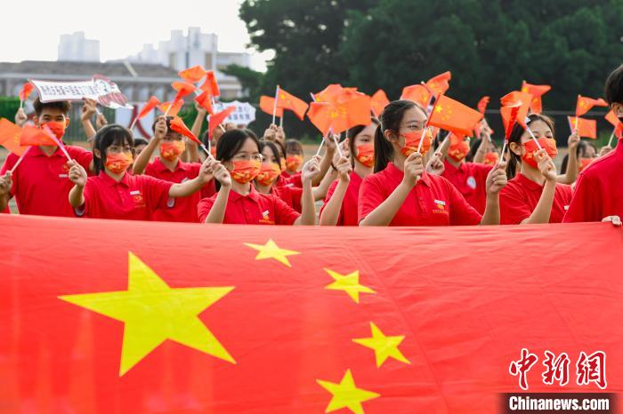 图为福建师范大学协和学院学子们参加升旗仪式，挥舞着手中的国旗。　林响 摄