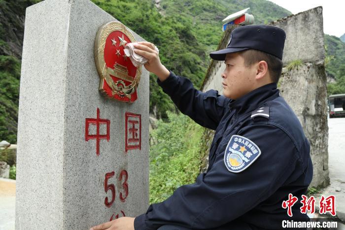 图为关天文正在擦拭53号界碑。　邹兴国 摄