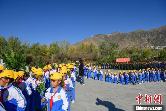 图为9月30日，在西藏自治区拉萨市烈士陵园，学生向革命烈士纪念碑献花。。　贡嘎来松 摄