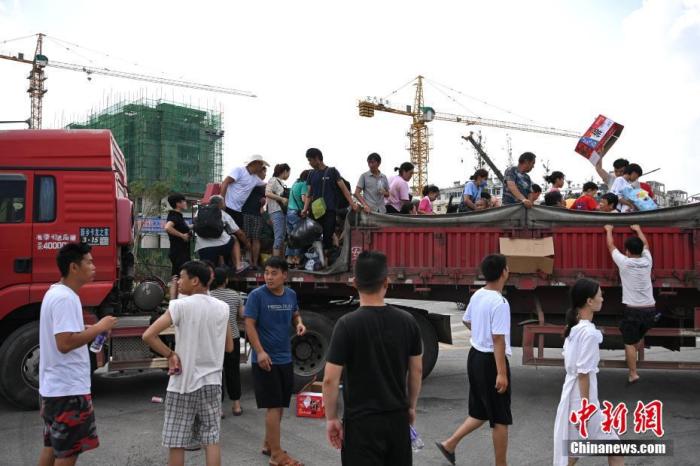 7月26日，河南省卫辉市，民众陆续登上一辆重型卡车，准备从市区转移至安都乡太公泉镇。 中新社记者 崔楠 摄