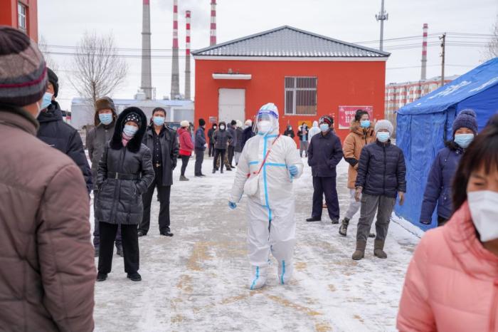 ↑11月10日，在黑河市爱辉区一小区，社区工作人员(中)组织居民排队领取免费生活物资。