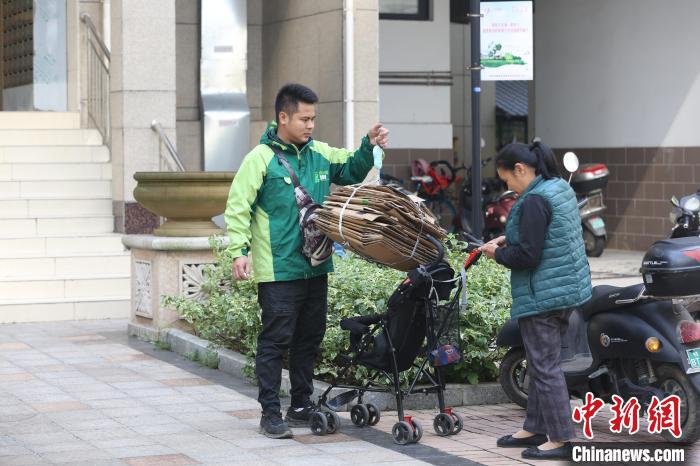 “回收小哥”在给纸皮称重。　朱柳融 摄