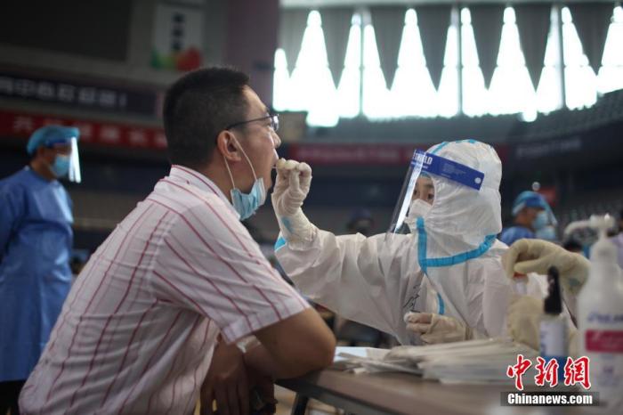 7月22日，江苏省南京市，设立在鼓楼区五台山体育馆的核酸检测点内，医务人员在为市民进行核酸检测取样。为进一步快速有效阻断新冠肺炎疫情扩散，江苏省南京市从7月21日开始对全市常住人口、外来人员开展全员核酸检测，目前正有序开展中。 中新社记者 泱波 摄