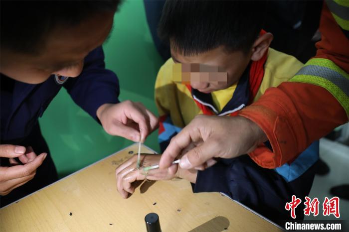 手与课桌安全分离后，消防员对遗留在学生手上的胶水进行彻底清理。　孙丽芳 摄