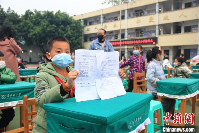 小学生展示知情同意书和新冠病毒疫苗接种健康状况登记表等相关材料。　梁钦卿 摄