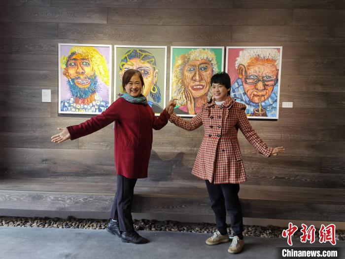 谢昕欣(右)和母亲徐渝江(左)在谢昕欣的画作前合影。　徐渝江供图