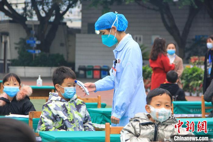 重庆市沙坪坝区中西医结合医院的医护人员正在给小学生进行体温检测。　梁钦卿 摄