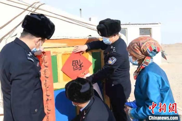 图为坚守在“生命禁区”的派出所民警帮牧民贴春联。　算井子边境派出所供图