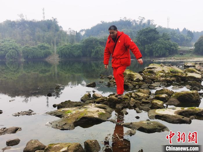 管道巡护工梁峰巡管时正趟过小安溪河。　刘燕 摄