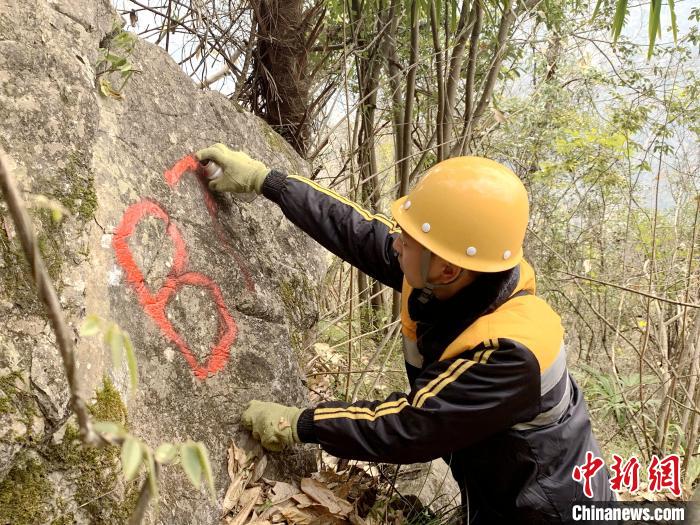 图为工作人员在半山腰上标记岩石。　马瑜阳 摄